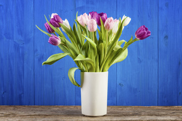 Tulips in a vase with blue wooden background