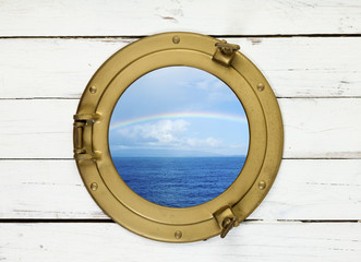 Rainbow over sea seen through porthole of wooden ship
