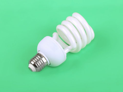 Energy saving fluorescent light bulb on green background