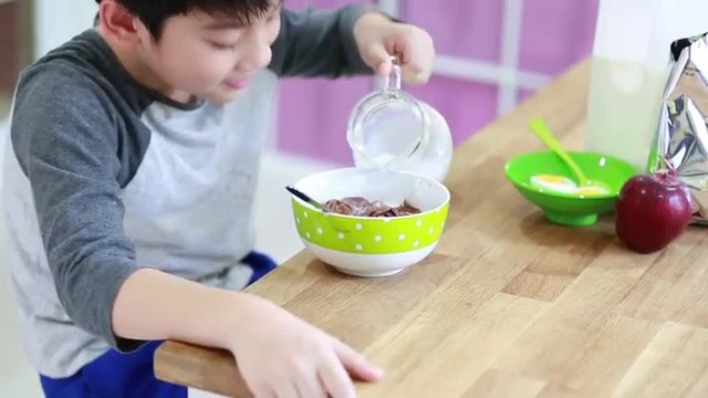 Little asian Boy eating cereal with milk with smile face