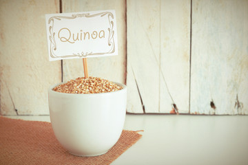 Some quinoa seeds in a bowl in the herbalist's. Empty copy space against a wooden background.