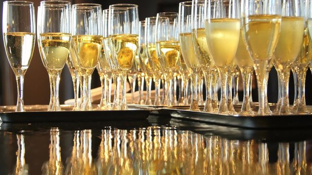 Champagne glasses sit on serving trays as people mingle.