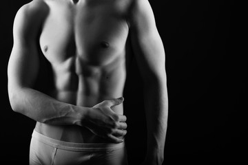 Fit young man with beautiful torso, isolated on black background