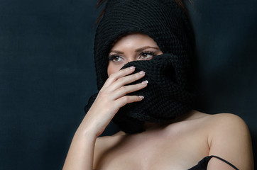 Beautiful face of a lady cover her head and face with a black wool scarf, shoulders uncovered