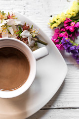 Cup of hot drink on saucer with flowers