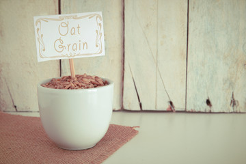 Some oat seeds in a bowl in the herbalist's. Empty copy space against a wooden background.