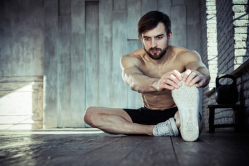 Sports. Man at the gym doing stretching exercises and smiling on the floor