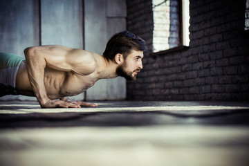 Sport. Young athletic man doing push-ups. Muscular and strong guy exercising.
