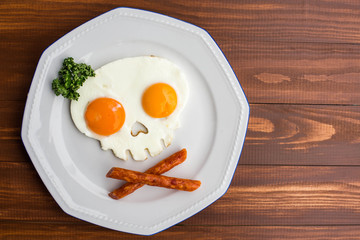 Fried eggs in the form of a skull on wooden table. Funny fried eggs. 