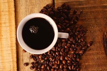 Tasse mit schwarzem Kaffee und Kaffeebohnen