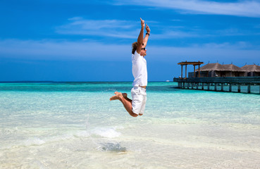 Mann springt am Strand der Malediven in die Luft