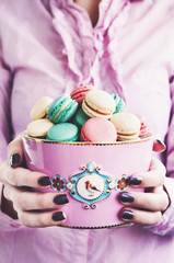 Girl holding pink bowl full of colorful macaroons - strawberry, vanilla and minty