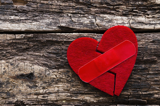 broken heart with a patch on a wooden background