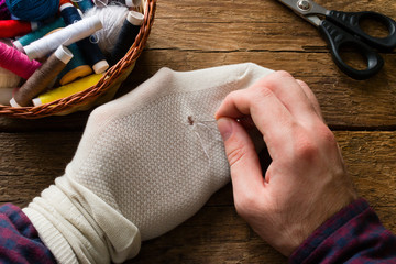 man sews socks on a wooden background