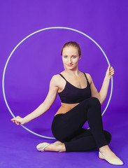 fitness and gym concept - young sporty woman with hula hoop at gym.on a blue background