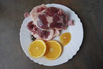 Fresh duck legs with orange and honey on the white plate.