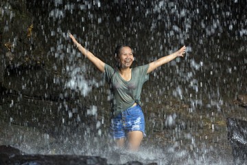 Happy woman under waterfall