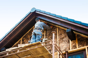 Naklejka na ściany i meble Construction worker thermally insulating house facade with glass