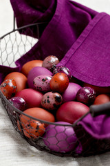 Easter eggs colored in purple and brown in the basket.