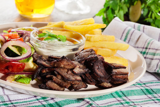 Grilled meat with French fries and fresh vegetables