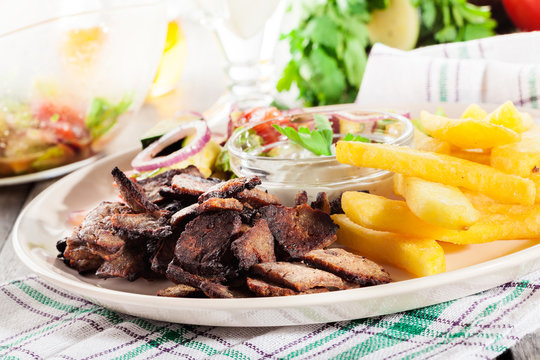 Grilled meat with French fries and fresh vegetables