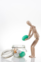 Burattino di legno con uova di Pasqua colorate in un barattolo di vetro