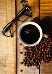 Brille, Kaffee und Kaffeebohnen auf Holzplanken