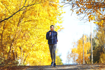 Young beautiful woman jogging in autumn park