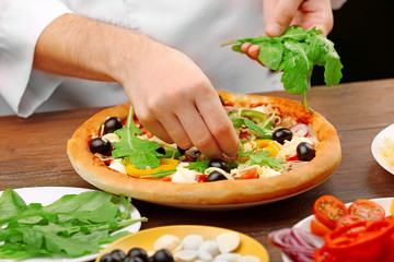 Cook making delicious pizza at the restaurant, close-up