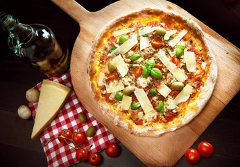 Foto op Plexiglas Heerlijke vers gebakken pizza op een houten peddel belegd met tomaten, parmezaan, basilicum, tomatensaus © Tijana