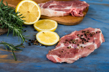Raw beef steak with lemon and rosemary  on a blue  wooden table