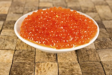 Caviar in the bowl on brown wooden table. Macro shot.