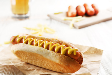Hot dog with fried potatoes on craft paper on wooden background