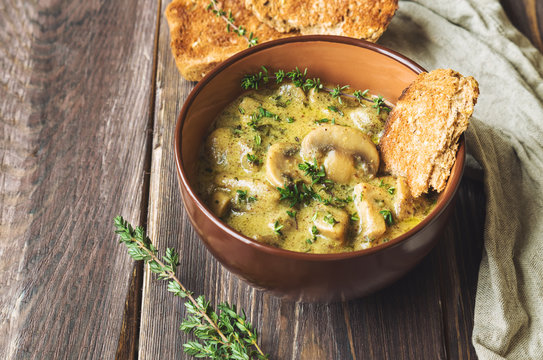 Mushroom sauce with thyme in a clay bowl with toasted bread