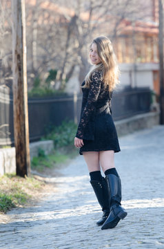Bronde lady walking outside in the town, wear lace dress, high boots and socks