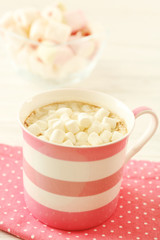 Mug of hot chocolate with marshmallows, on light wooden background