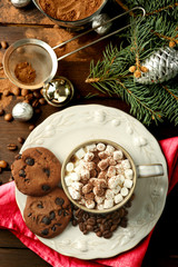 Mug of hot chocolate with marshmallows, fir tree branch on wooden background