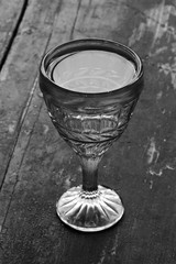 vintage shot glass with vodka on an old wooden black table closeup. black and white photo