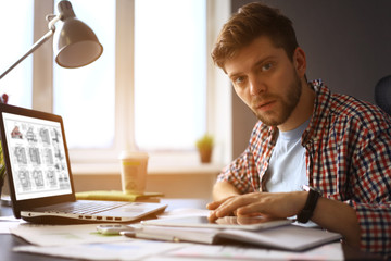 Enjoying good working day. Confident young man working on laptop while sitting at his working place 