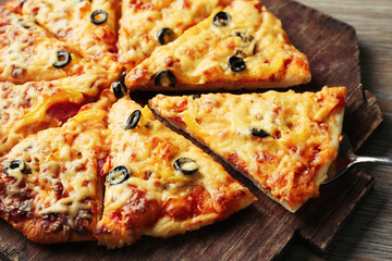 Delicious sliced pizza on wooden board, close up