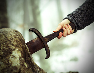 knight tries to remove Excalibur sword in the stone