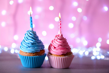 Two cupcakes with candle on a glitter background