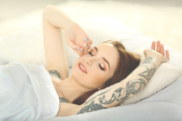 Obraz na płótnie Canvas Attractive woman with tattoo lying on the bed
