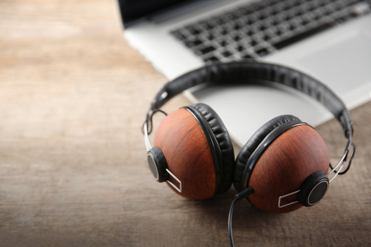 Laptop and earphones on wooden background