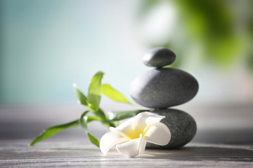 Spa stones with tropical flower and bamboo on blurred background