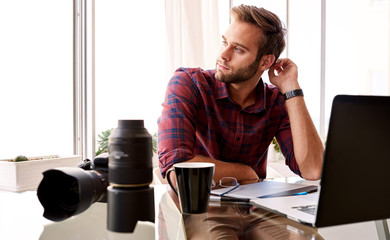 Entrepreneurial photographer looking off camera at his desk