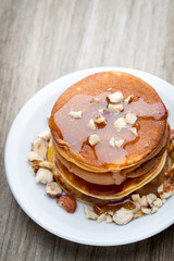 Stack of homemade pancakes with honey on wooden background.