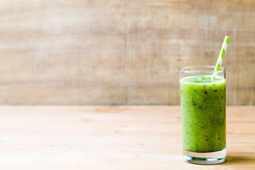 Healthy green smoothie in a glass on old wood.