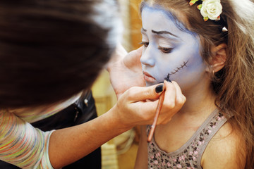 little cute child making facepaint on birthday party, zombie Apocalypse facepainting, halloween preparing