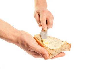Hand holding knife spreading butter on bread
